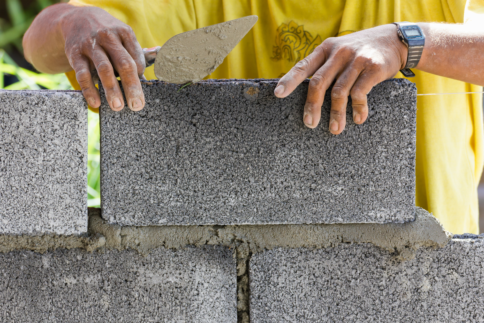 Bricklayer putting down another row of bricks in site